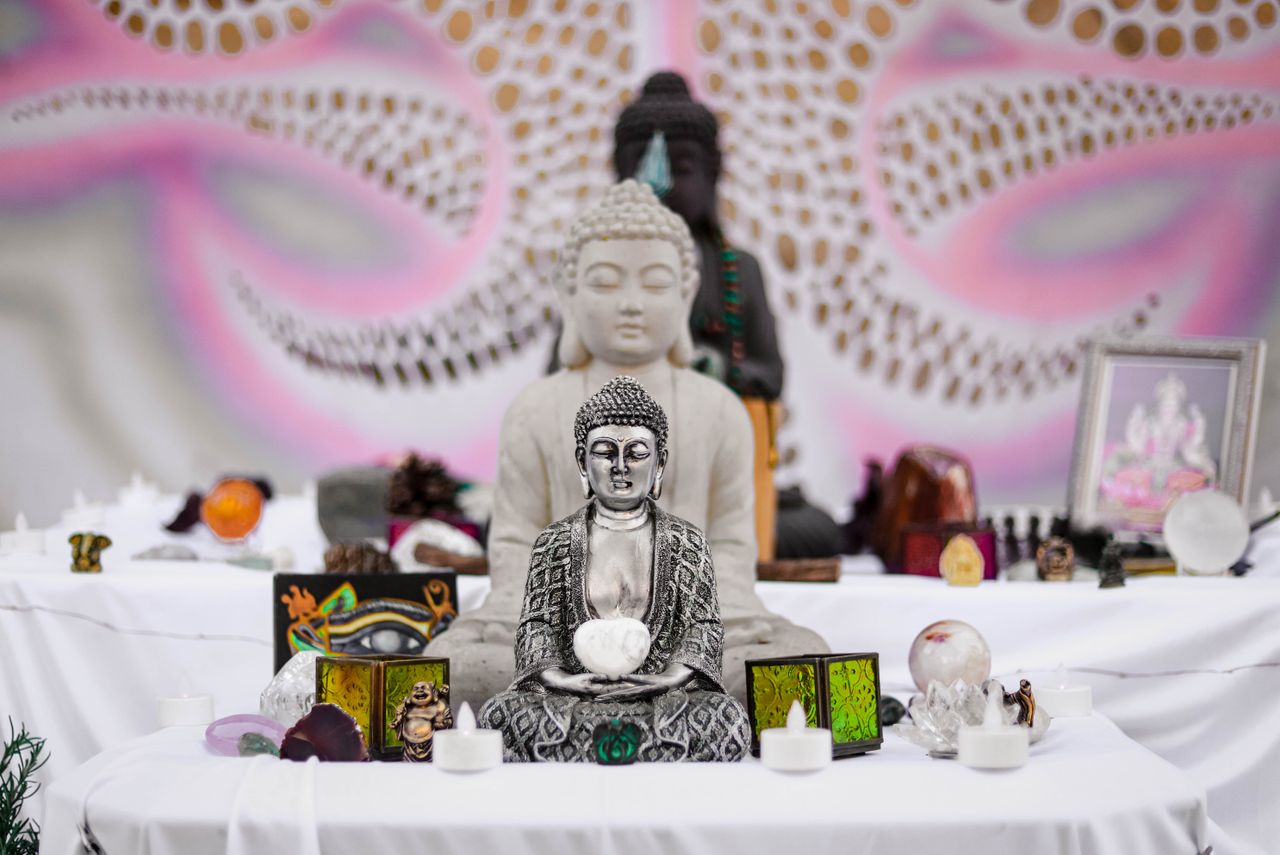 A detailed view of a Buddhist altar featuring multiple Buddha statues and spiritual objects.